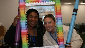 two educators with crayon and picture frame props