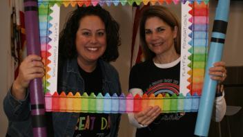 two educators with crayon and picture frame props