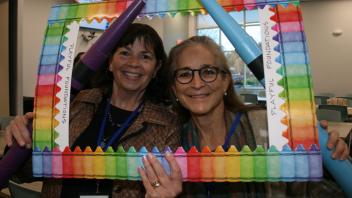two educators with crayon and picture frame props