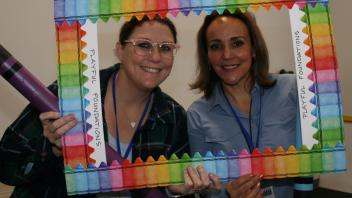 two educators with crayon and picture frame props