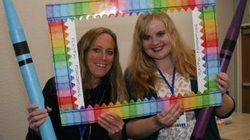 two educators with crayon and picture frame props