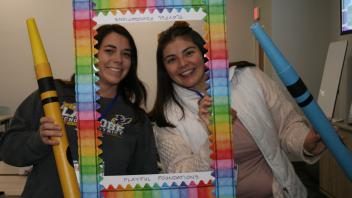 two educators with crayon and picture frame props