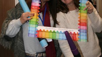 two educators with crayon and picture frame props