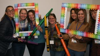 7 educators with crayon and picture frame props
