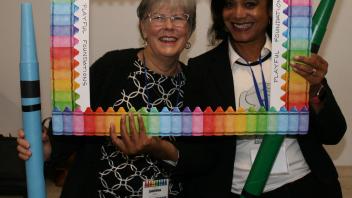 two educators with crayon and picture frame props