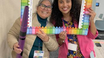 two educators with crayon and picture frame props