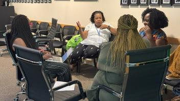 4 women seated talking in chairs