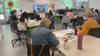 approximately 25 women sitting in a class doing math