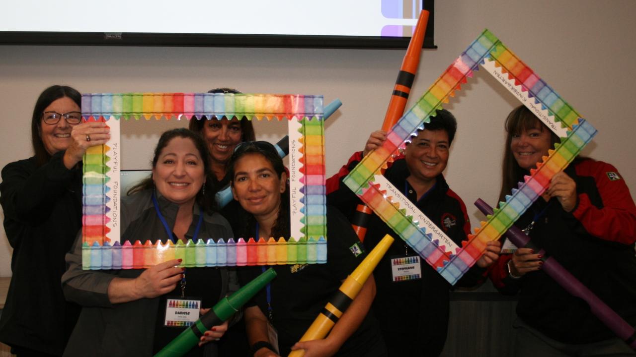 four educators with crayon and picture frame props